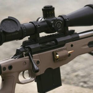 Close-up of a custom precision rifle featuring the Deadline 2.0 Action with a mounted scope and a cartridge in the side loading port, designed for high-performance shooting.
