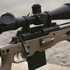 Close-up of a custom precision rifle featuring the Deadline 2.0 Action with a mounted scope and a cartridge in the side loading port, designed for high-performance shooting.